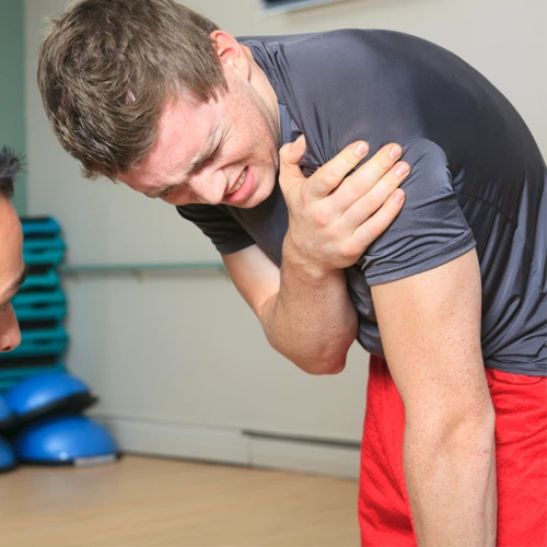 A young athlete in pain, holding their injured shoulder